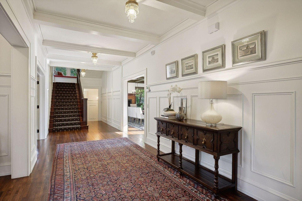 Entryway with hardwood floors, a patterned rug, and a staircase leading to an upper level.