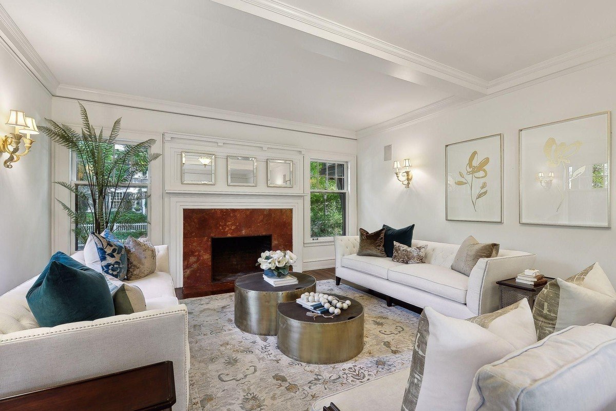 Living room with white sofas, patterned rug, and gold accent tables.