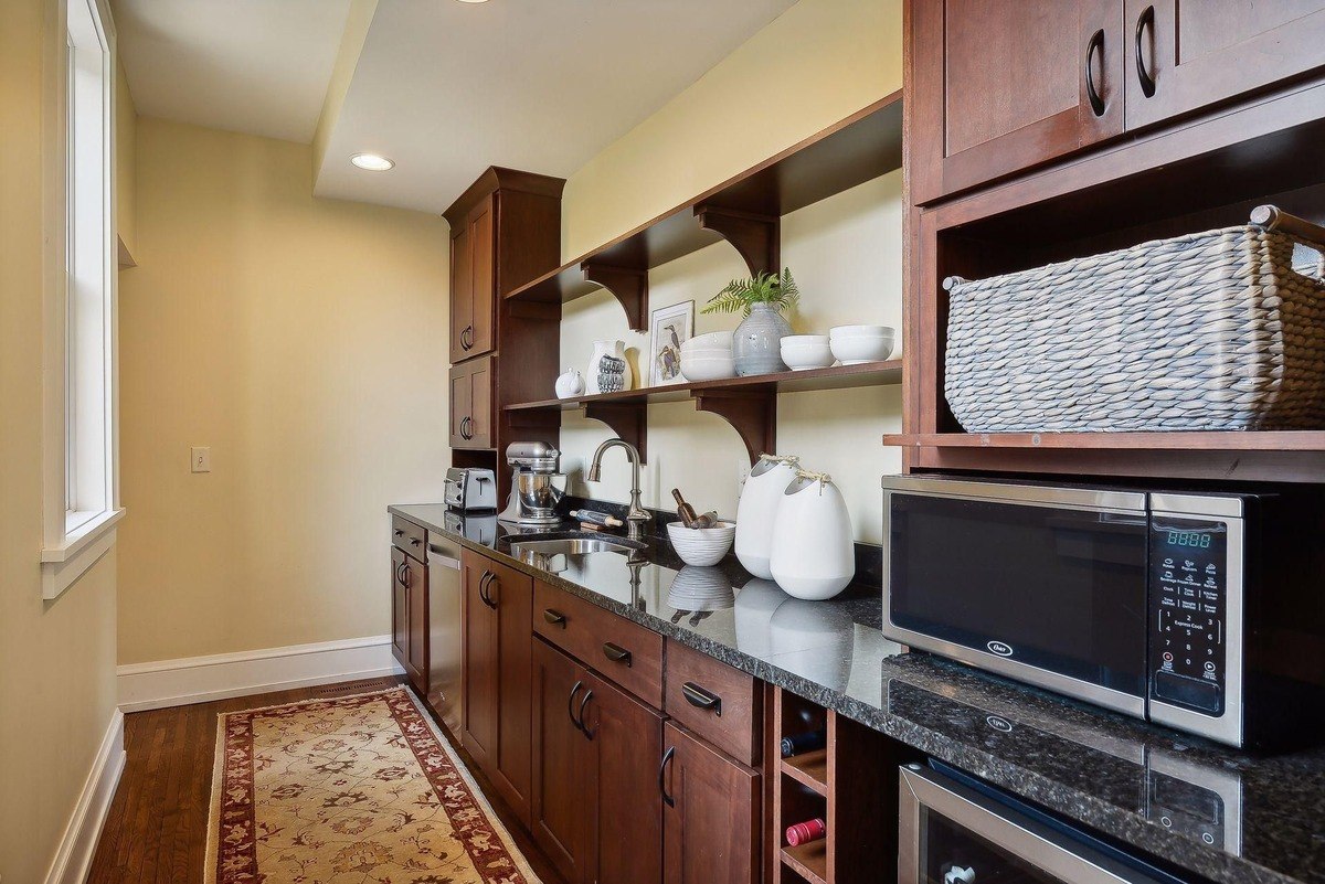 Kitchenette with dark wood cabinets, granite countertops, and a patterned rug.