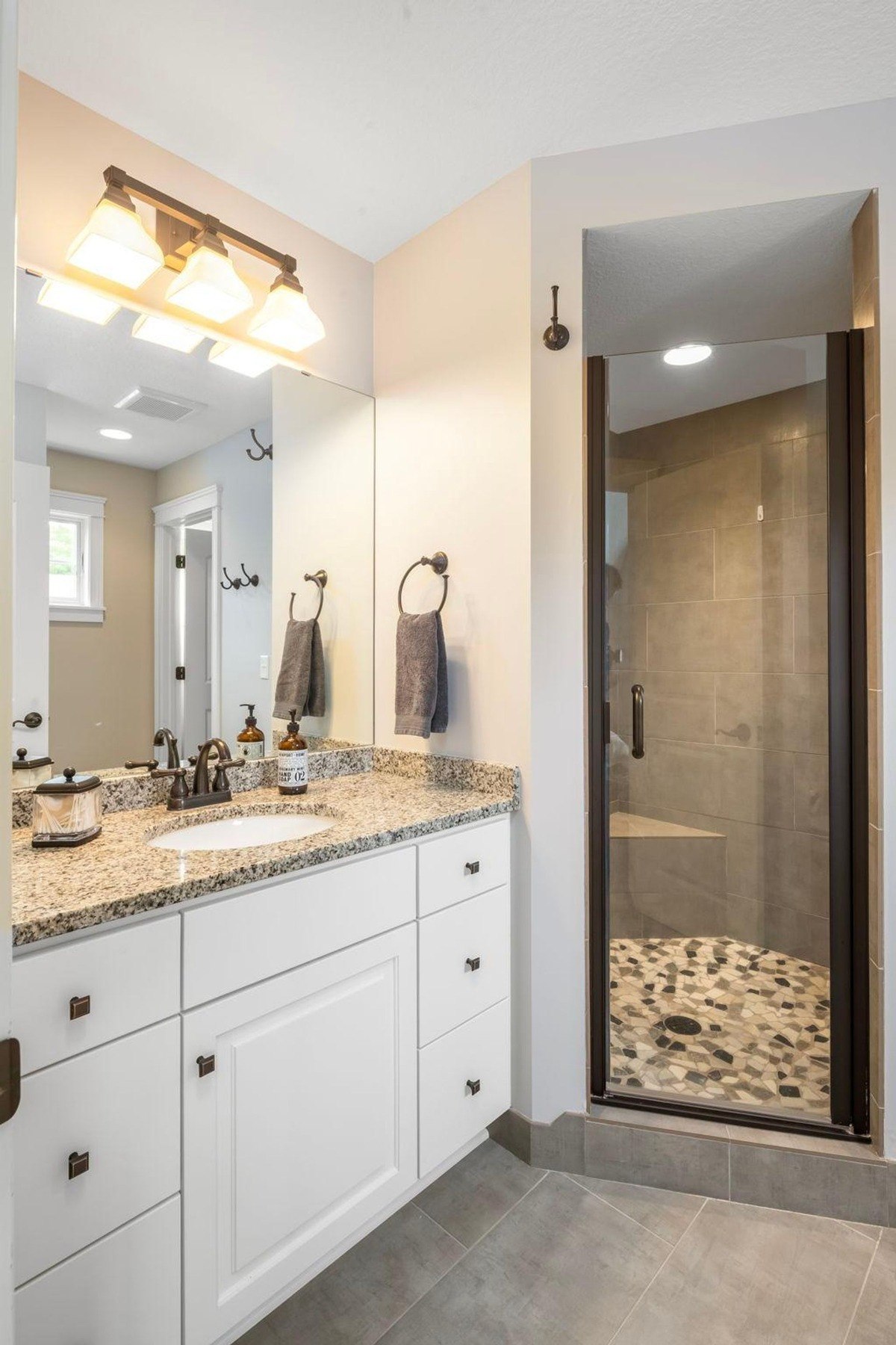 Modern bathroom with granite countertops and a glass-enclosed shower.