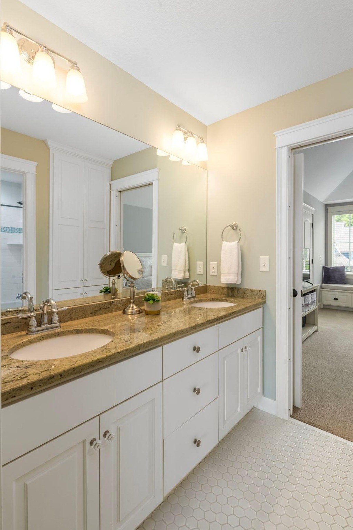 Dual-sink bathroom with granite counters and hexagonal floor tiles.