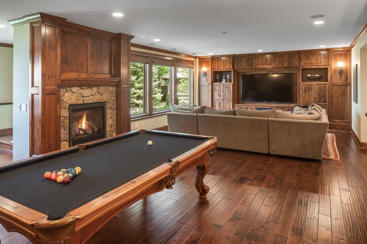 Game room with a fireplace, pool table, and large entertainment system.