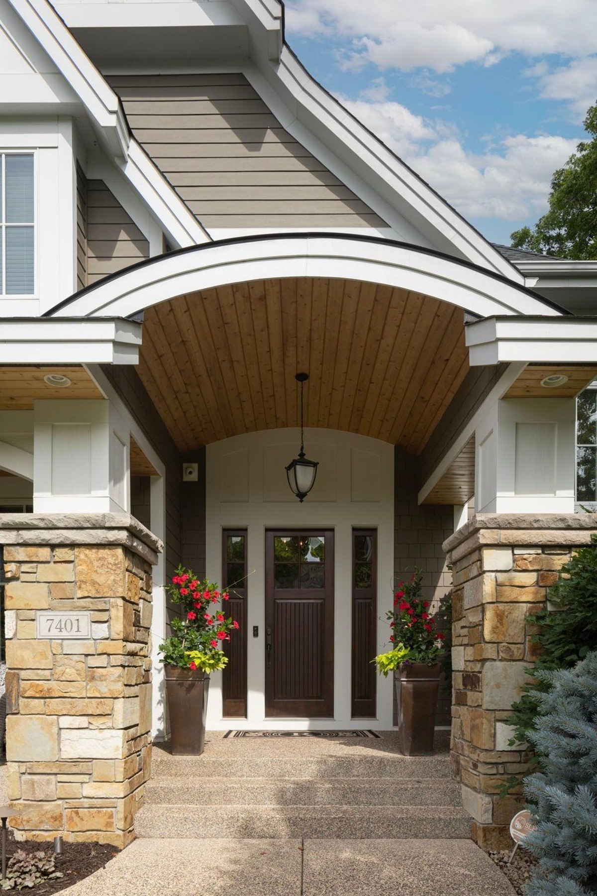 .Close-up view of the arched front entryway with stone columns and wooden accents.