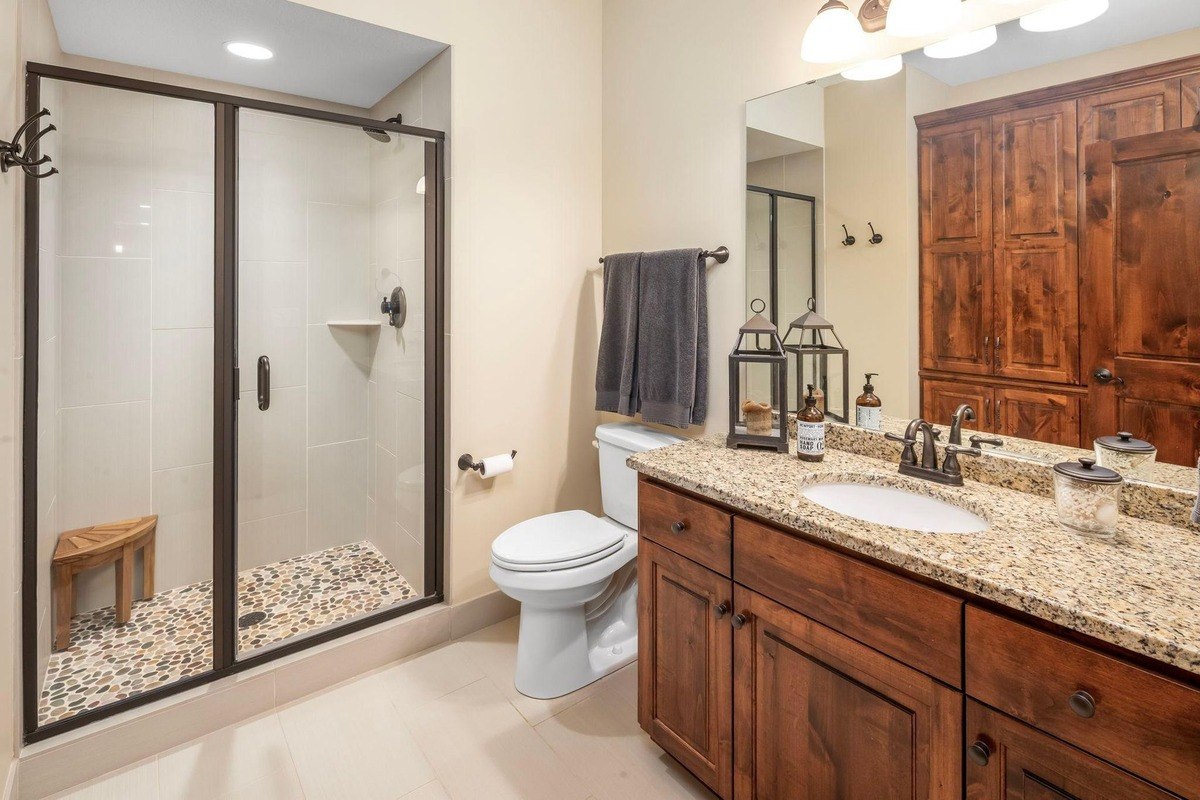 Bathroom with a tiled walk-in shower and rustic wood vanity.