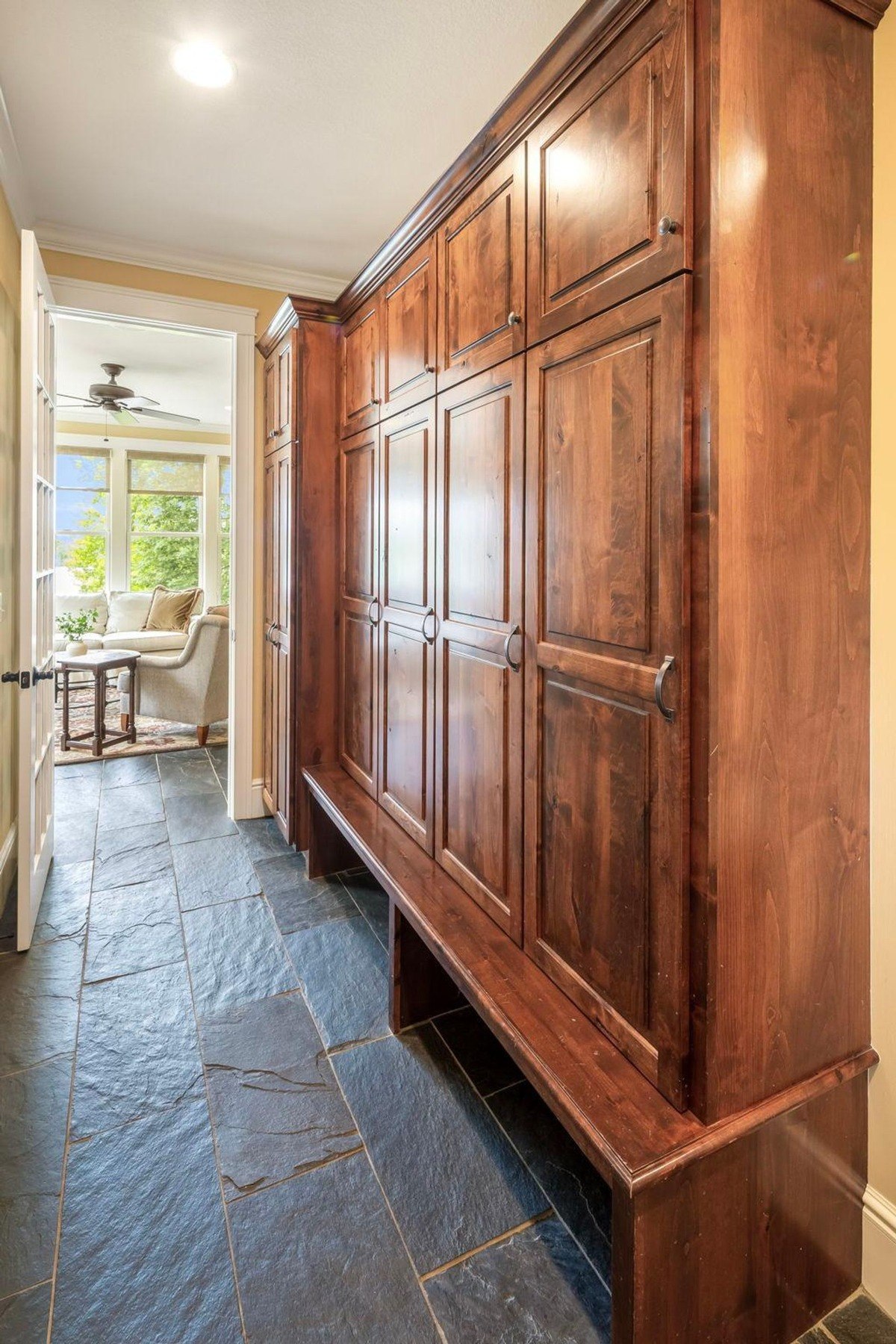 Mudroom with a built-in bench and a row of wood cabinets offers ample storage space and a functional entryway.