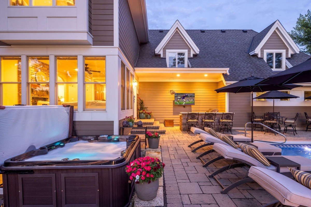 Relaxing outdoor space features a hot tub, a pool, lounge chairs, and a covered patio with a TV, creating a perfect spot for entertaining and unwinding.