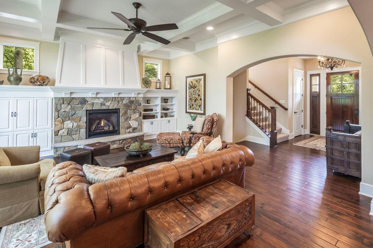 Cozy living room featuring a stone fireplace, coffered ceiling, and built-in cabinetry.