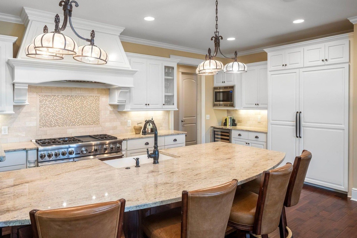 Modern kitchen with a large island, white cabinetry, and stainless steel appliances.