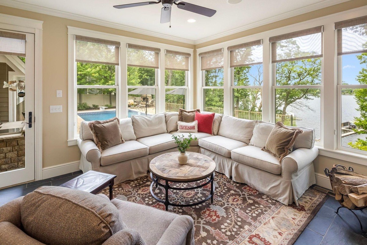 Sunroom with a sectional sofa, overlooking the backyard pool and lake.