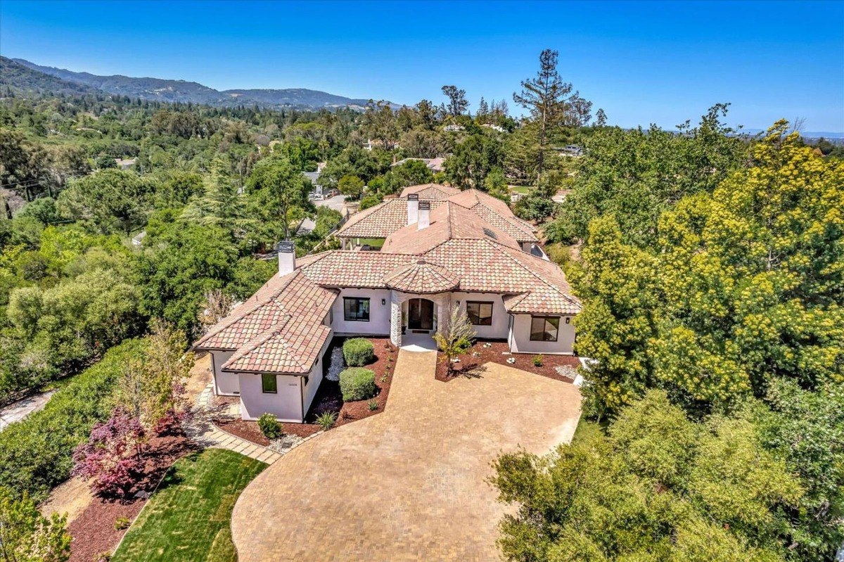 Aerial view of a spacious Mediterranean-style home surrounded by lush greenery.