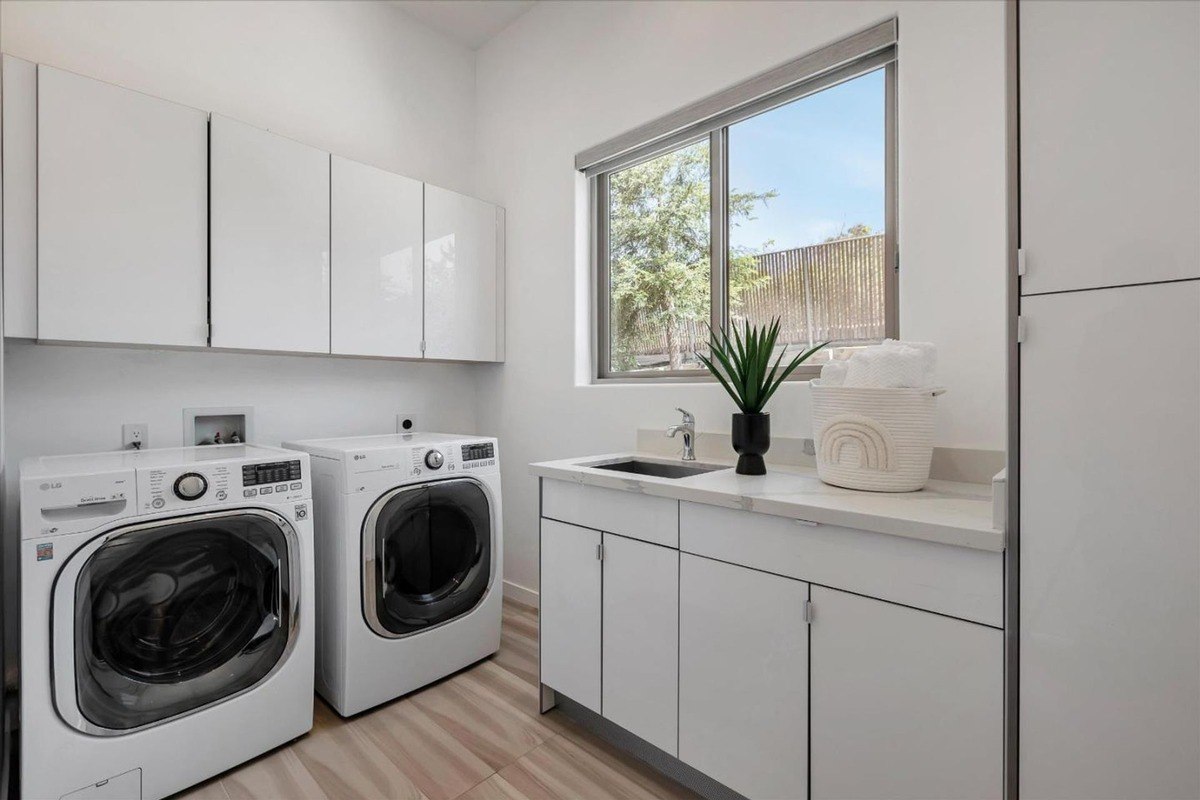 Laundry room a bright laundry room with a front-loading washer, dryer, and white cabinets.