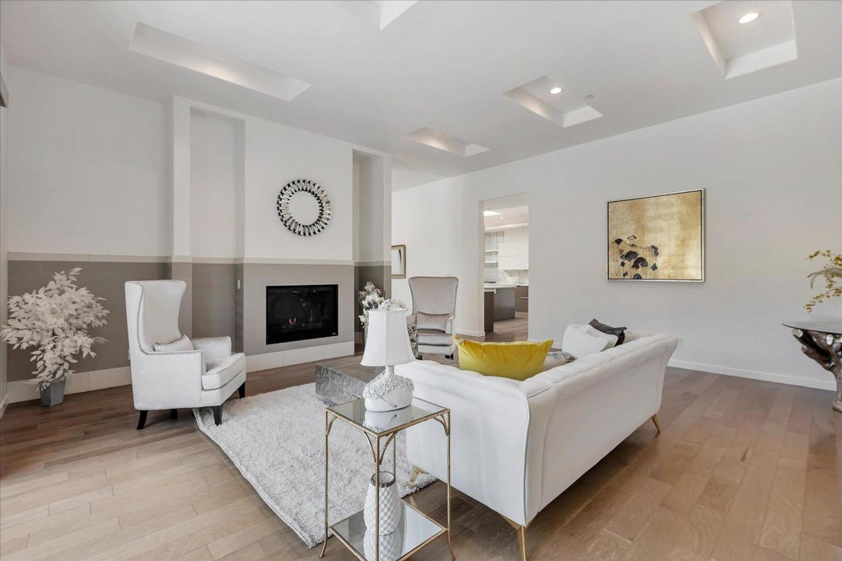 Living room with a fireplace, neutral-toned furniture, and an elegant accent wall.