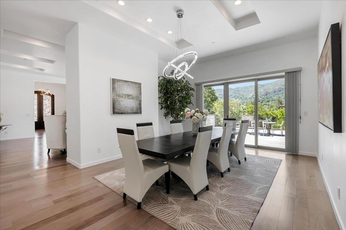 Dining room with large windows overlooking outdoor views and a contemporary chandelier.