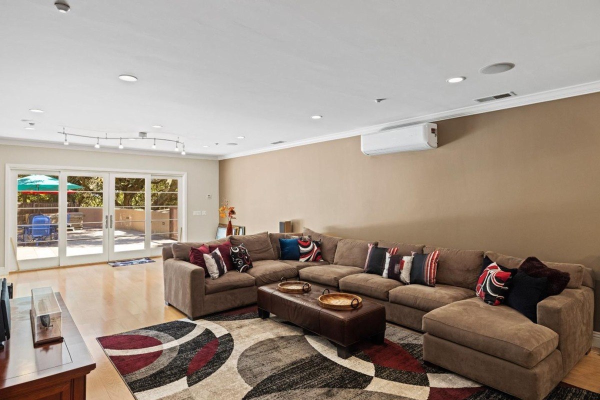 Family room with a large sectional sofa, a coffee table, and French doors leading to an outdoor patio, creating a comfortable and inviting atmosphere.