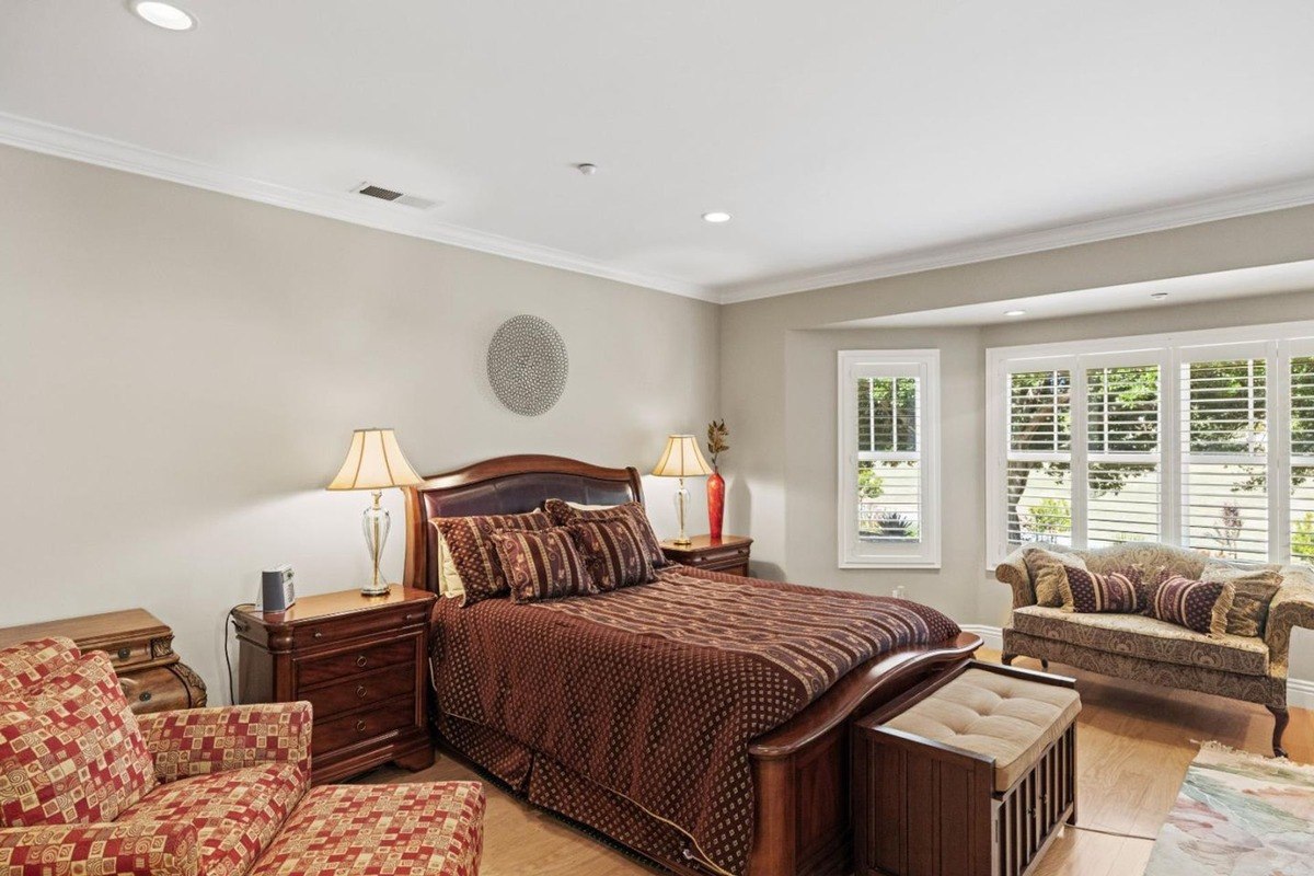 Bedroom with a king-sized bed, a pair of nightstands, and a seating area with a loveseat and ottoman, creating a cozy and inviting atmosphere.