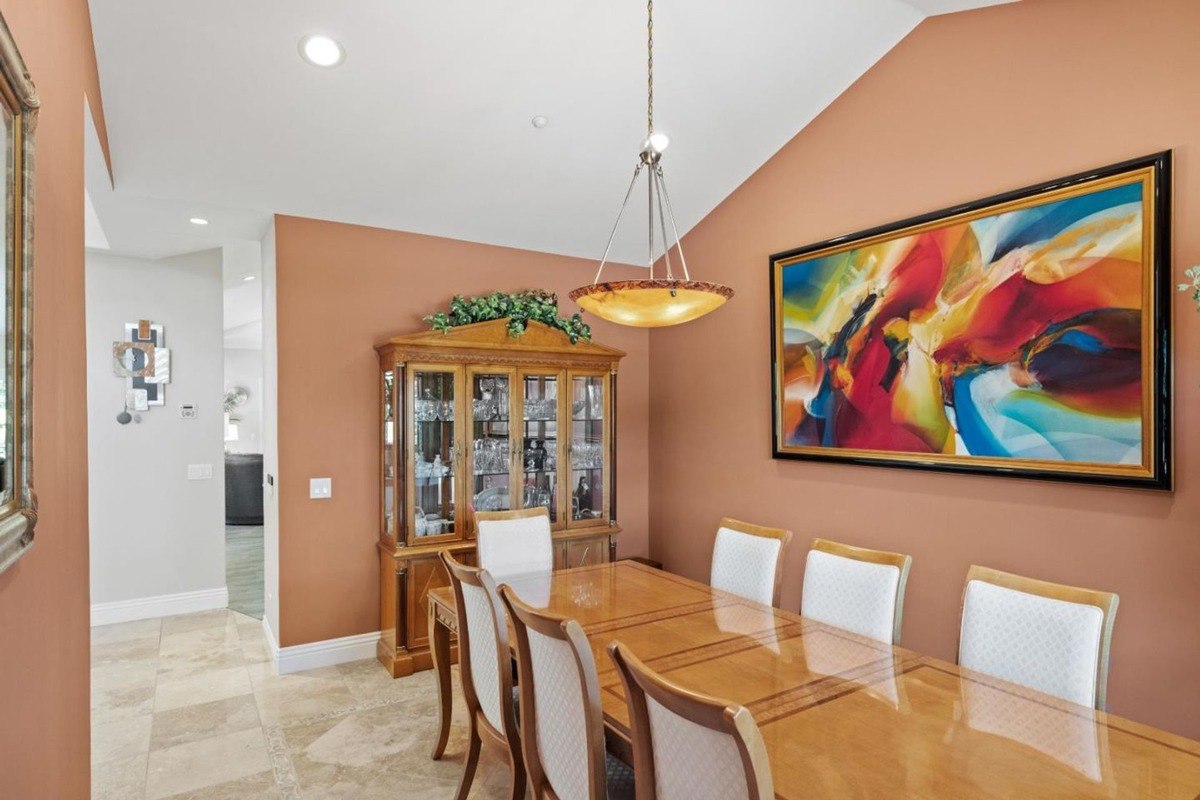 Formal dining room with a warm color palette, featuring a wood dining table and chairs, a china cabinet, and a vibrant abstract artwork.