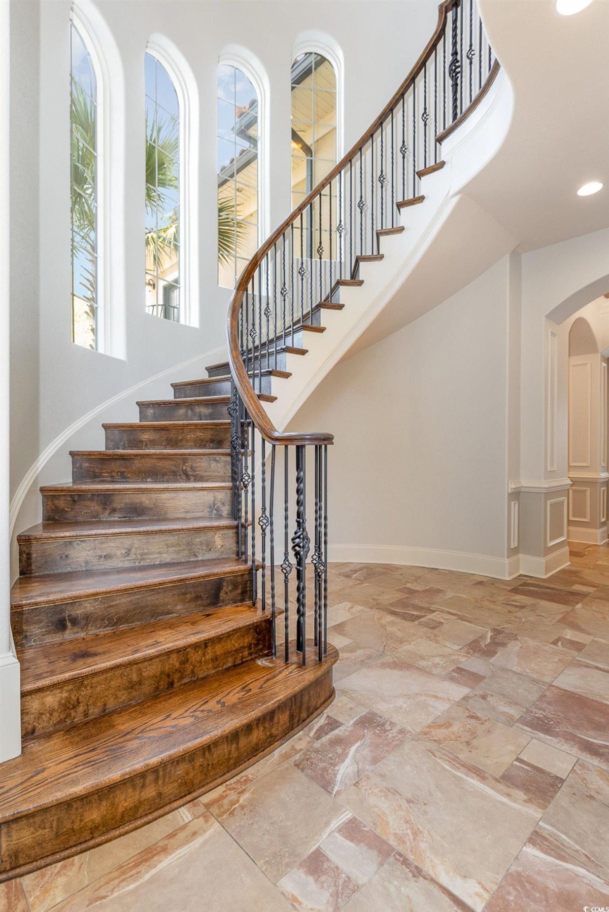 Staircase is curved with wood steps and a metal railing.