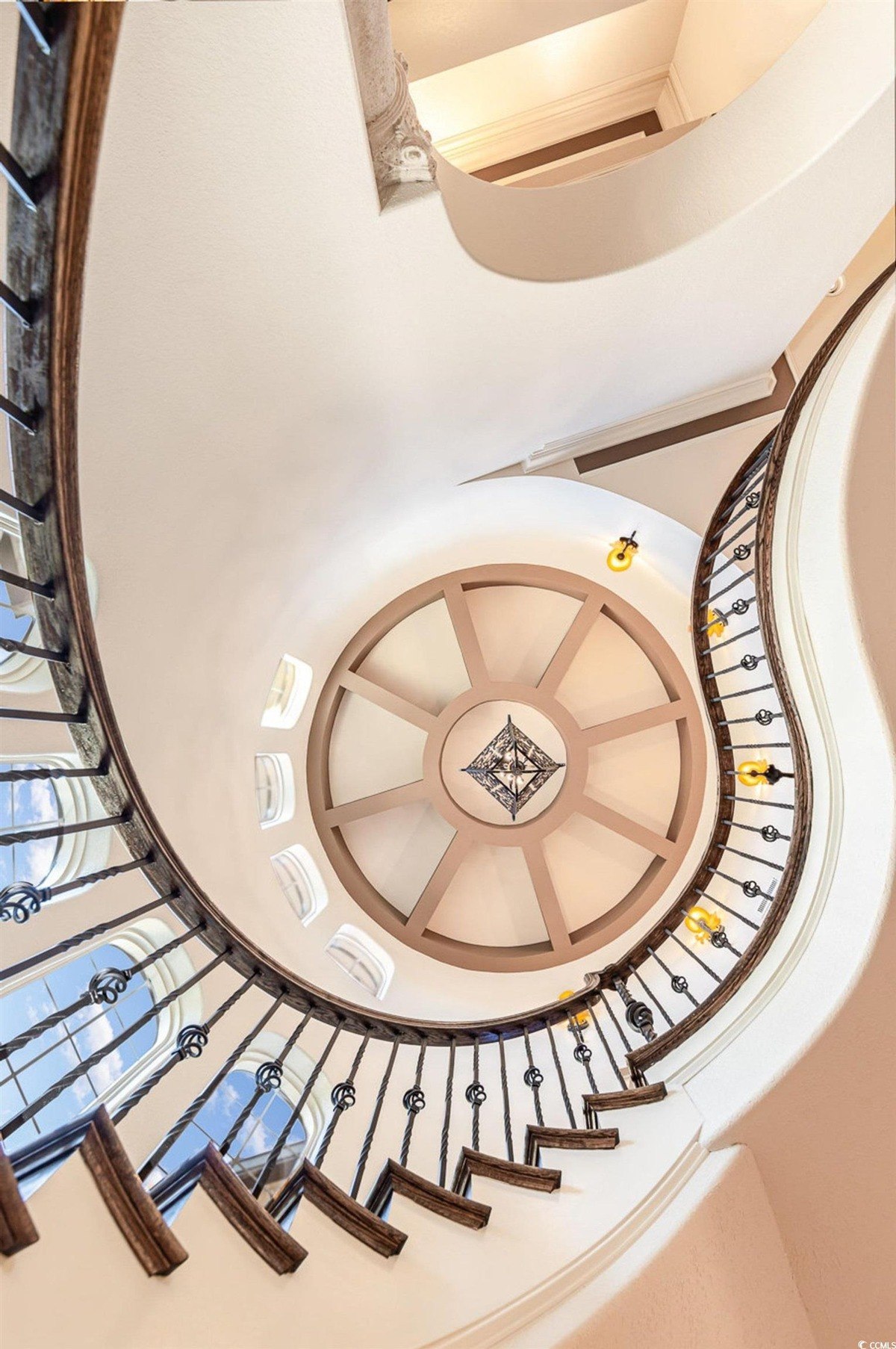 Staircase is spiral with wood steps and a metal railing, and has a circular skylight above.