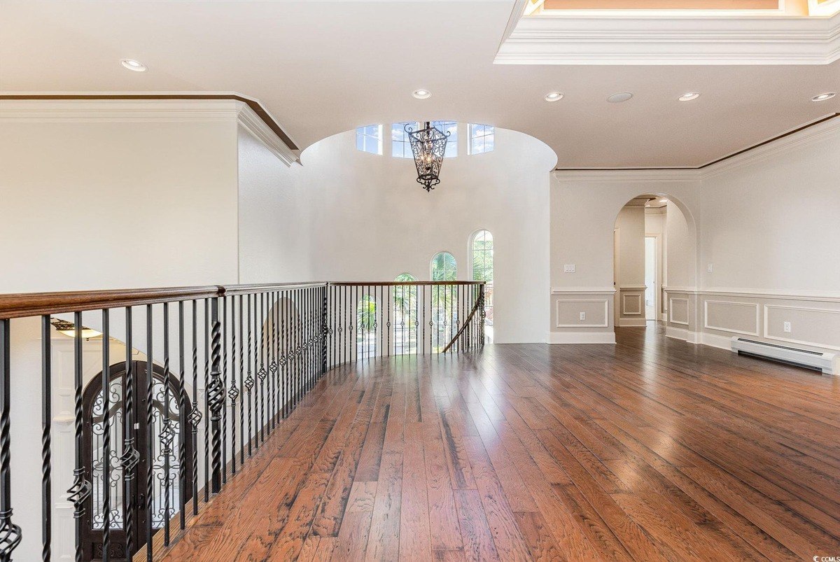 Landing has hardwood floors, a railing, and a view of a staircase below.