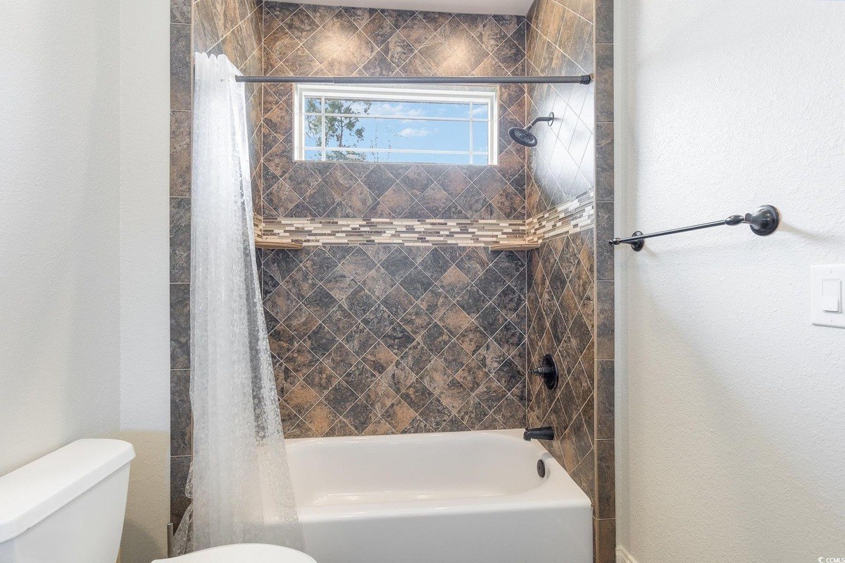 Bathroom has a shower/tub combo with brown tile and a white shower curtain.