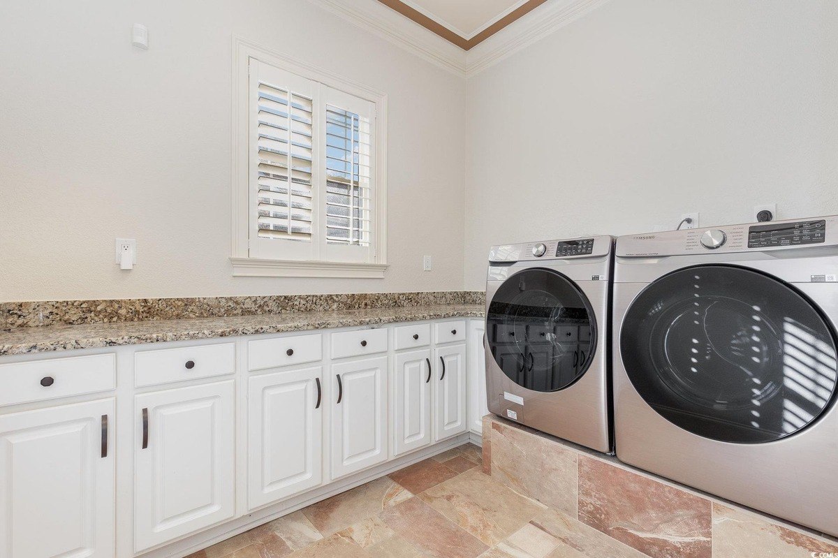 Laundry room has white cabinets, granite countertops, and a washer and dryer.