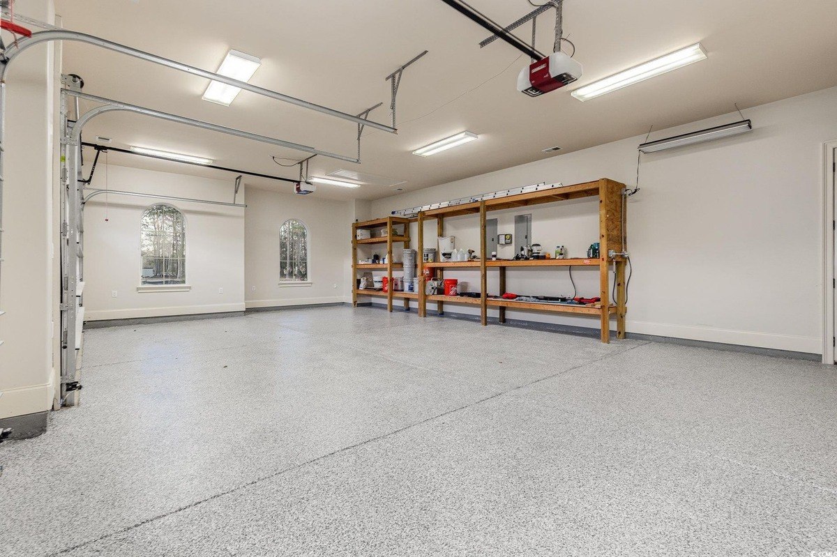 Garage has an epoxy floor and wooden shelving units.