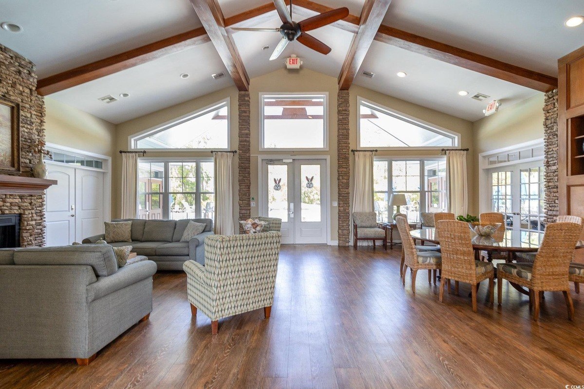 Large room has hardwood floors, exposed beams, and plenty of seating.