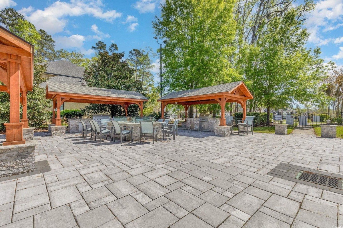 Outdoor patio area has two gazebos with grills and fire pit, surrounded by trees and landscaping.