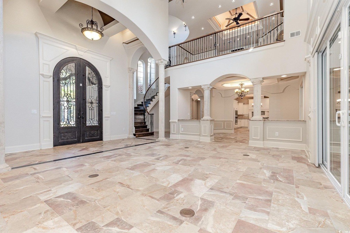 Great room has high ceilings, a staircase, and tile floors.