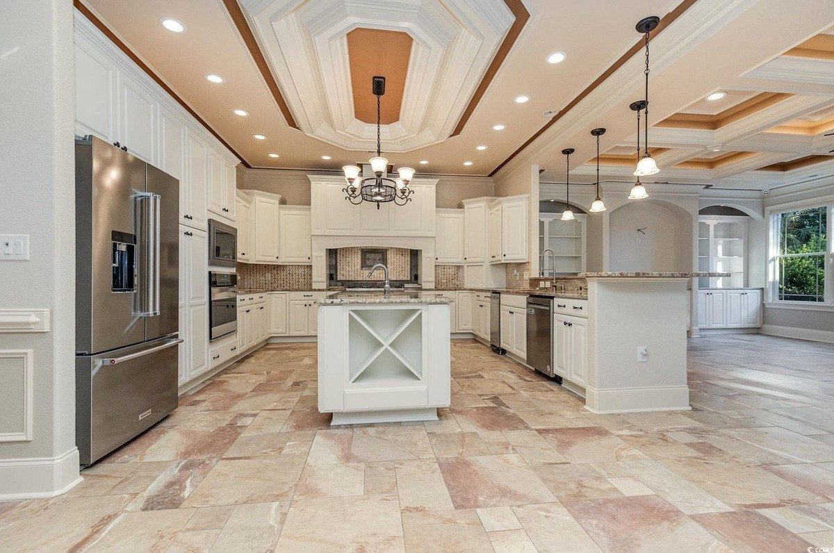 Kitchen has white cabinets, granite countertops, and a large island.