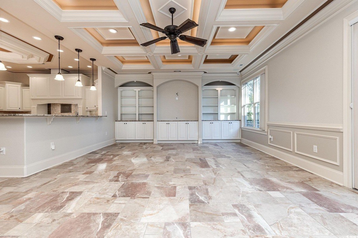 Room has coffered ceiling, tile floor, and built-in cabinets.