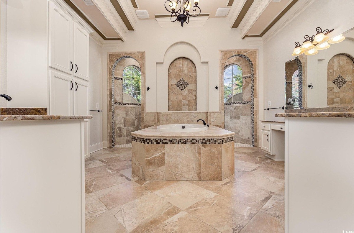 Bathroom has a large soaking tub, tile floors, and white cabinets.