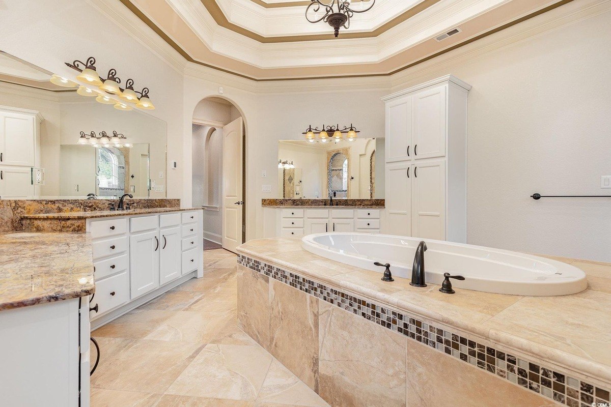 Bathroom has a large soaking tub, double vanities, and tile floors.