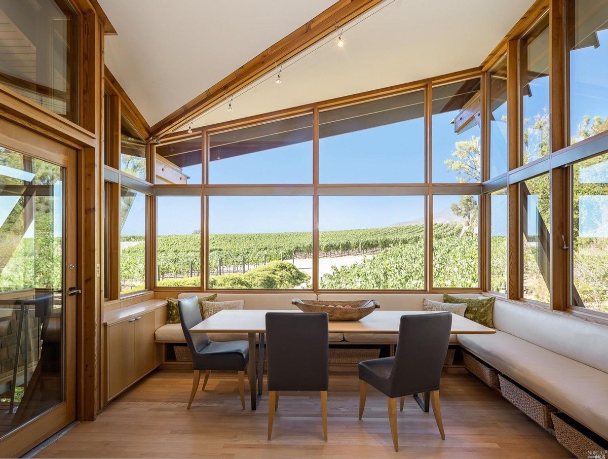 Breakfast nook framed by large wooden-framed windows offers expansive vineyard views and built-in seating.