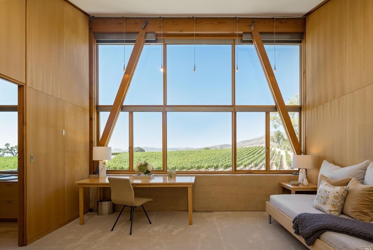 Private workspace includes a desk setup by a window with vineyard scenery framed by wooden beams.