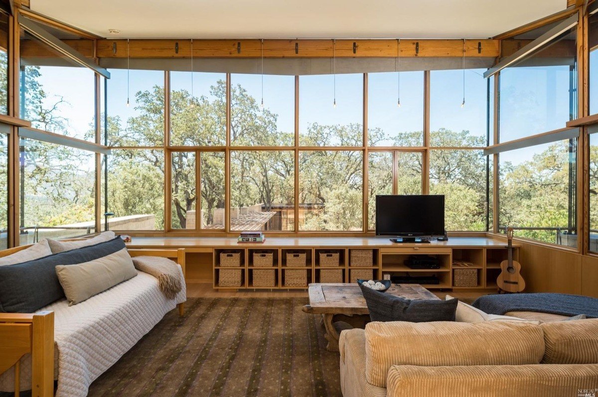 Family room highlights a cozy seating area with a large window overlooking surrounding trees.