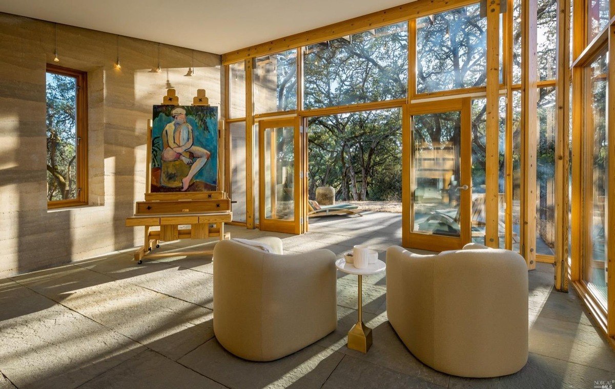 Cozy artist’s corner featuring an easel near floor-to-ceiling glass doors and natural stone walls.