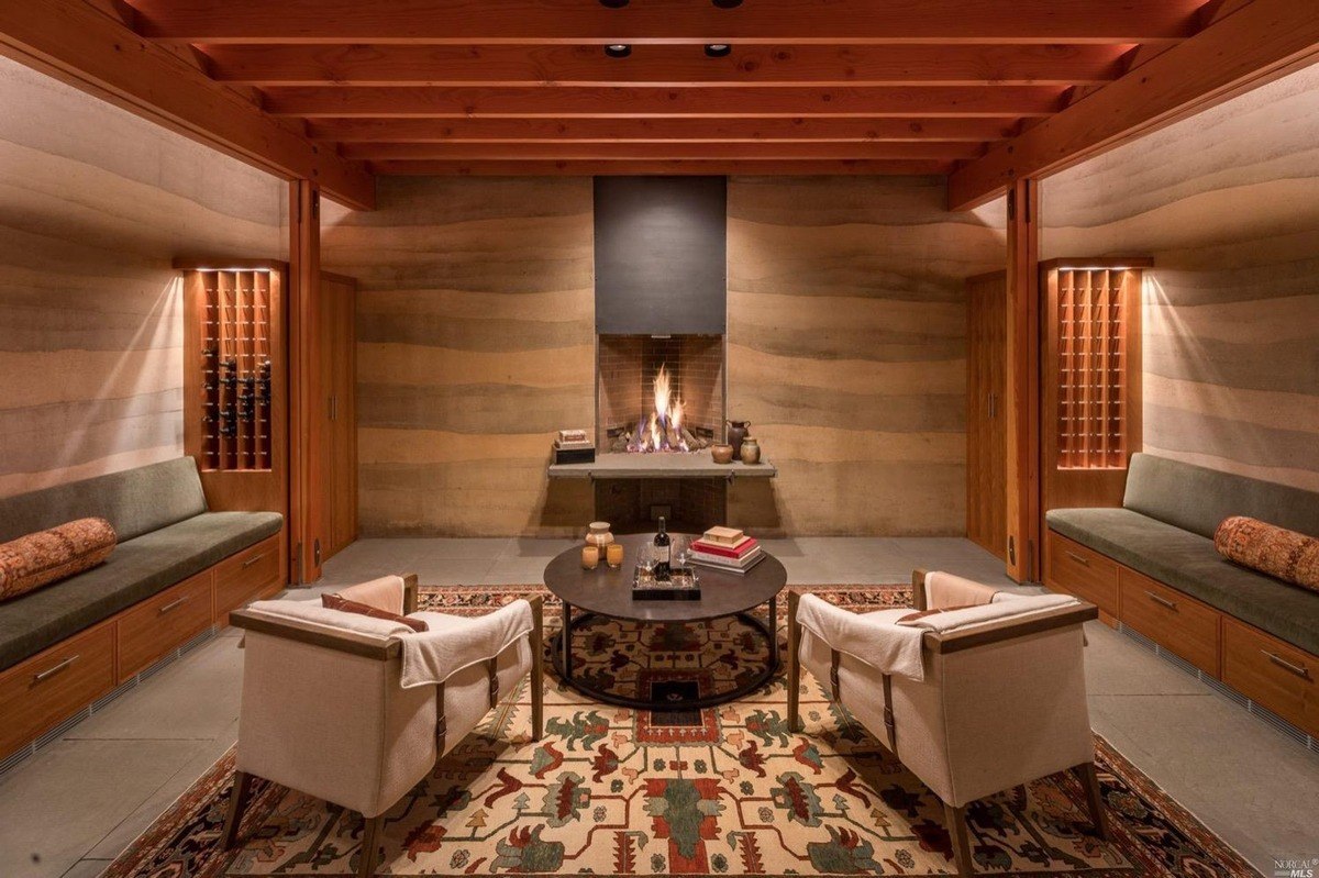 Cozy lounge area with a central fireplace, wooden beams, and built-in seating creating a warm ambiance.