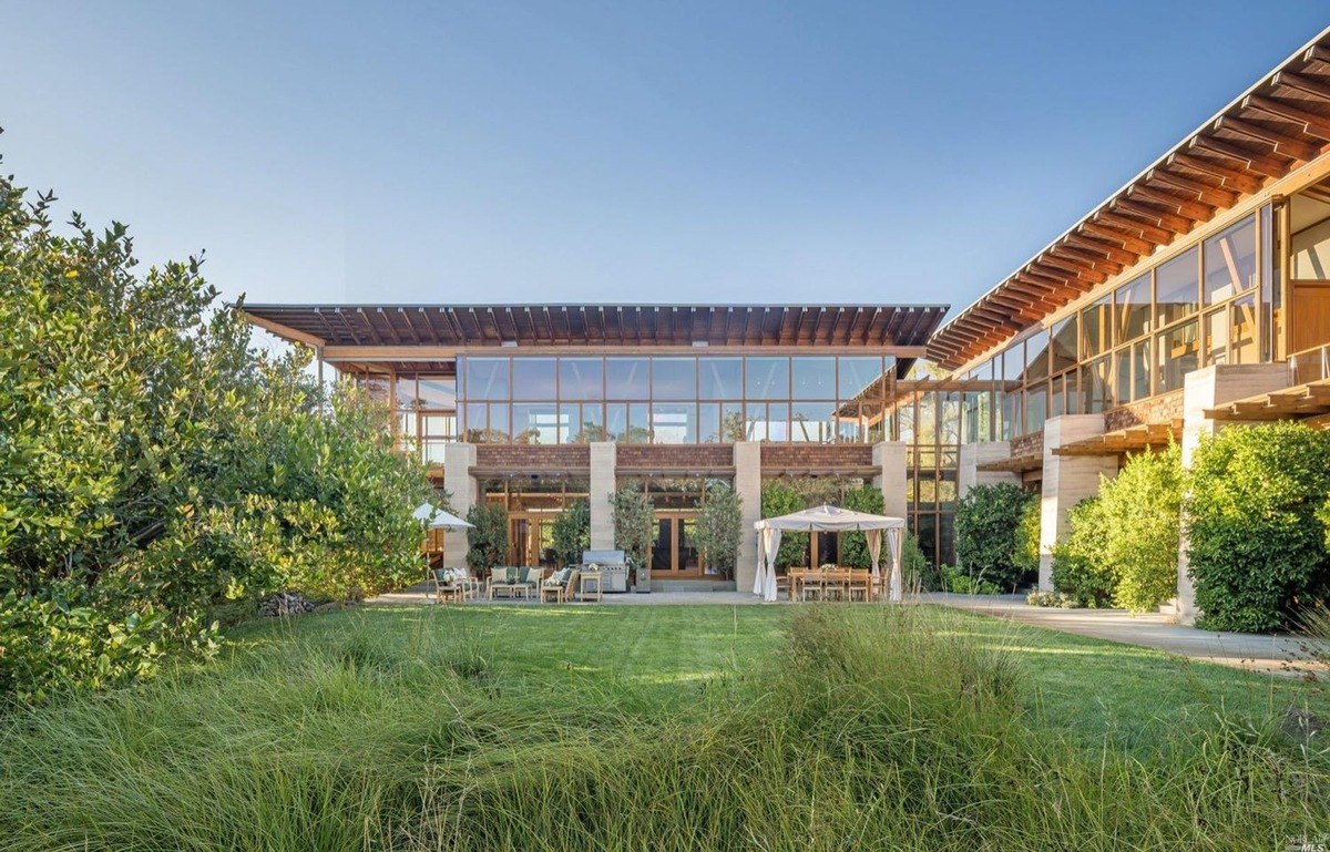 Garden-side view featuring a large glass facade with outdoor dining arrangements and greenery.