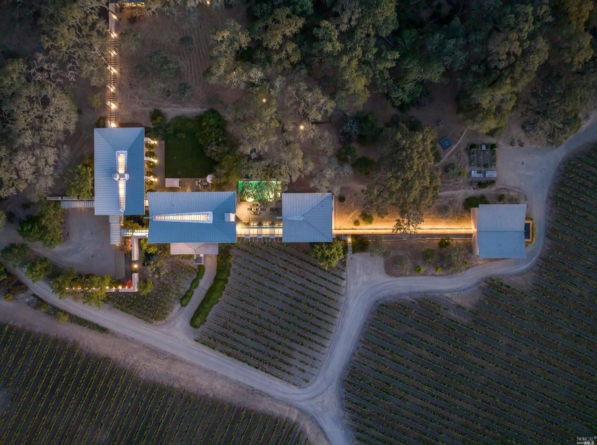 Aerial view of the entire estate at twilight, showcasing its interconnected buildings and vineyard rows.