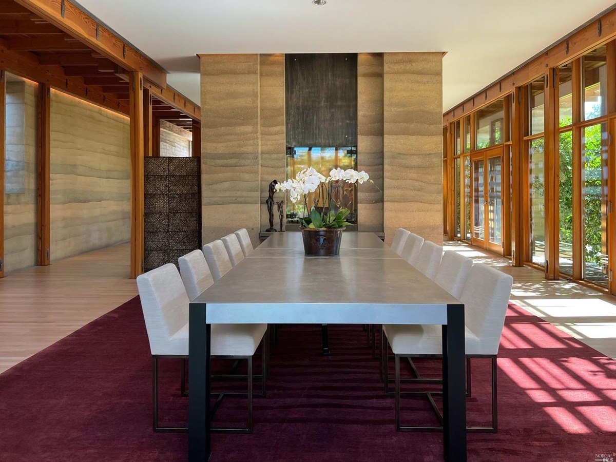 Spacious dining area featuring a long contemporary table, surrounded by elegant seating and large glass doors opening to garden views.