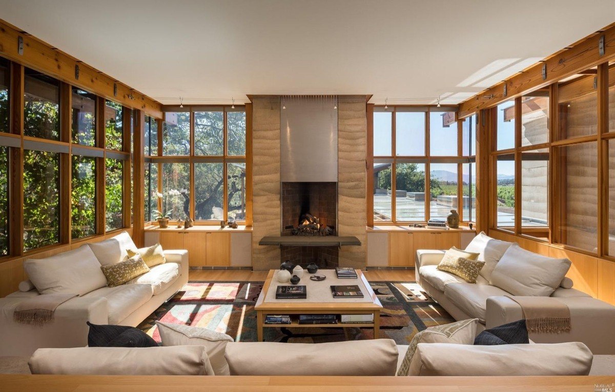 Cozy sitting area centers around a modern fireplace with panoramic views from surrounding large windows.