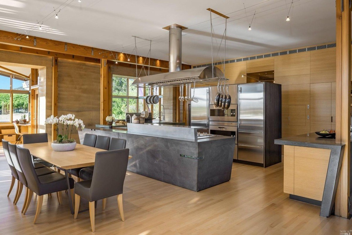 Kitchen includes a sleek stone island, modern appliances, and an adjacent dining area with wooden finishes.