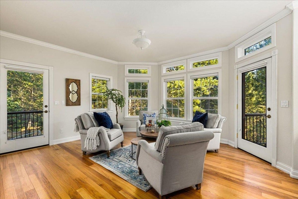 Bright sitting room offers multiple windows, elegant furniture, and French doors leading to the outdoors.