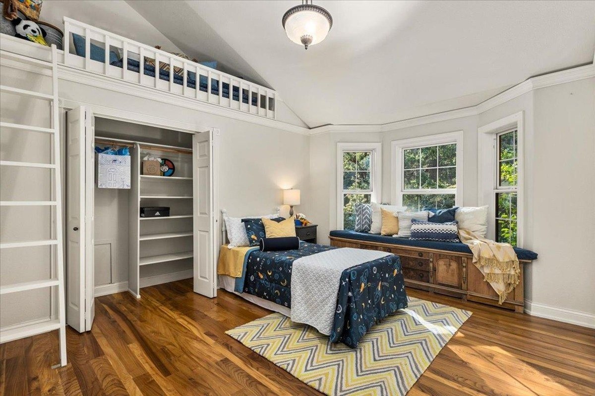 Cozy bedroom with a built-in loft, seating nook, and cheerful accents of blue and yellow.