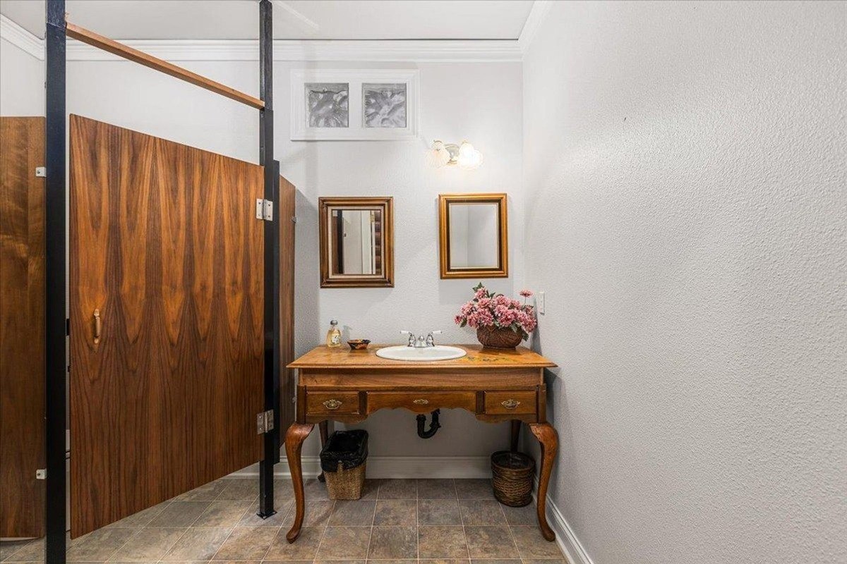 Bathroom vanity combines vintage charm with wooden accents and polished fixtures in a compact layout.