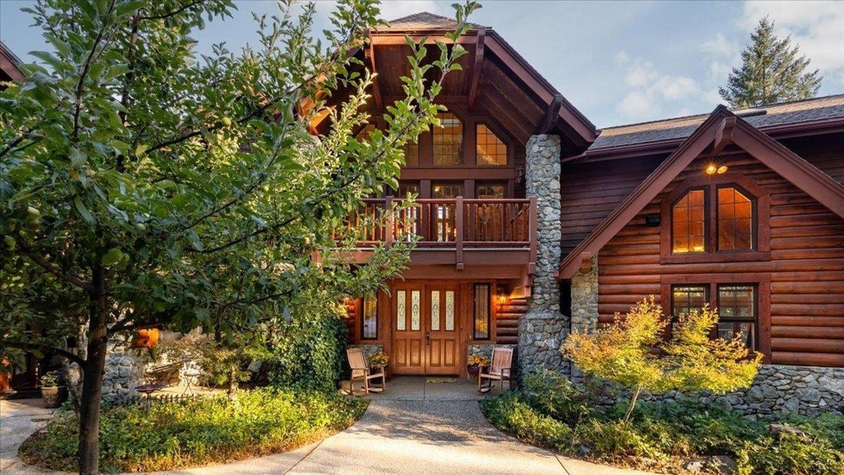 Entrance highlights a spacious porch with rustic stone columns and wooden rocking chairs for added charm.