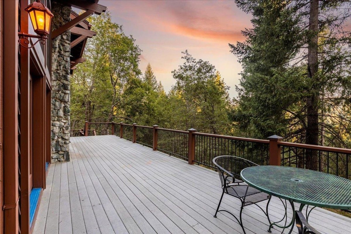 Elevated dining area on the deck provides a serene spot with outdoor seating overlooking tall pine trees.