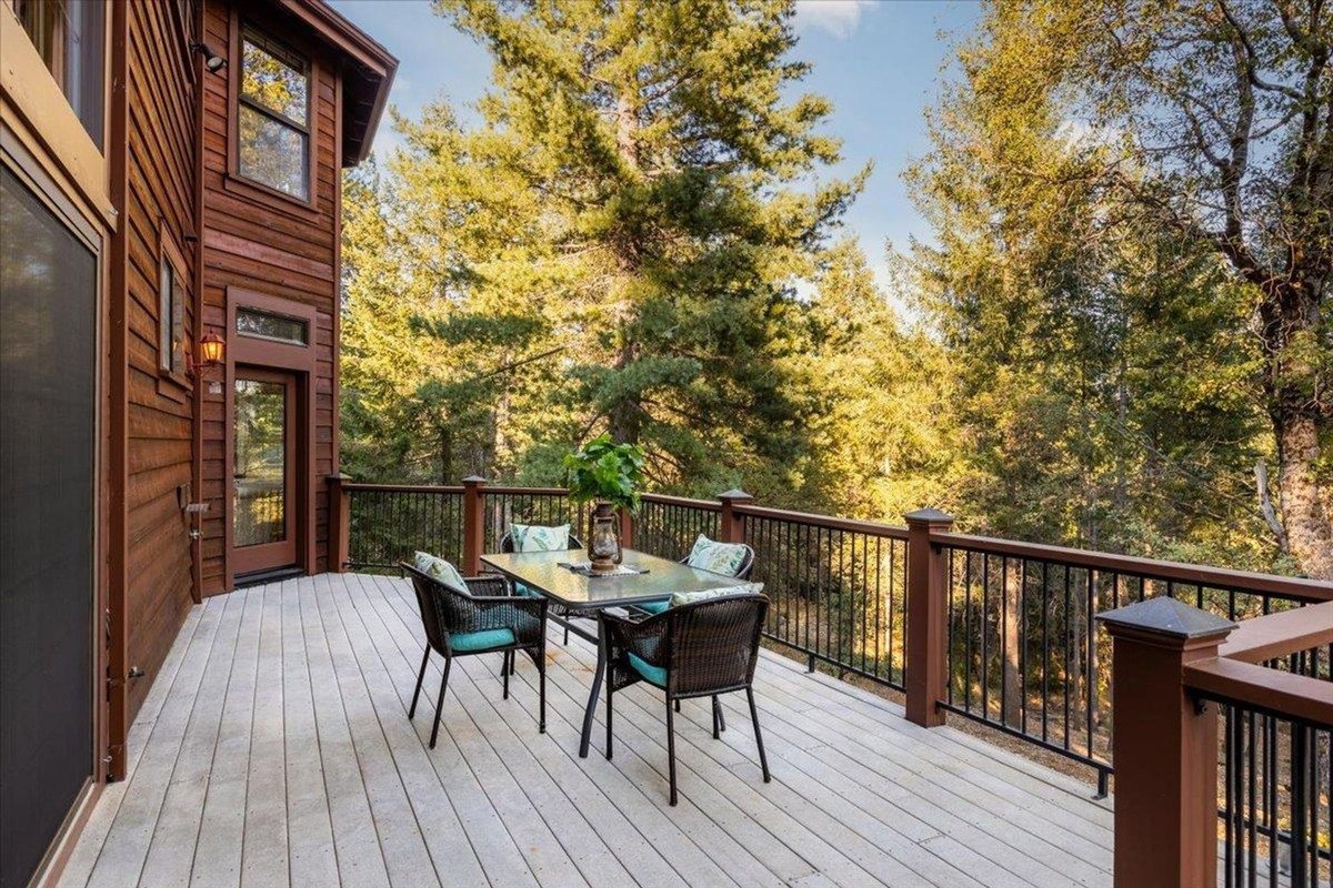 Elevated dining area on the deck provides a serene spot with outdoor seating overlooking tall pine trees.