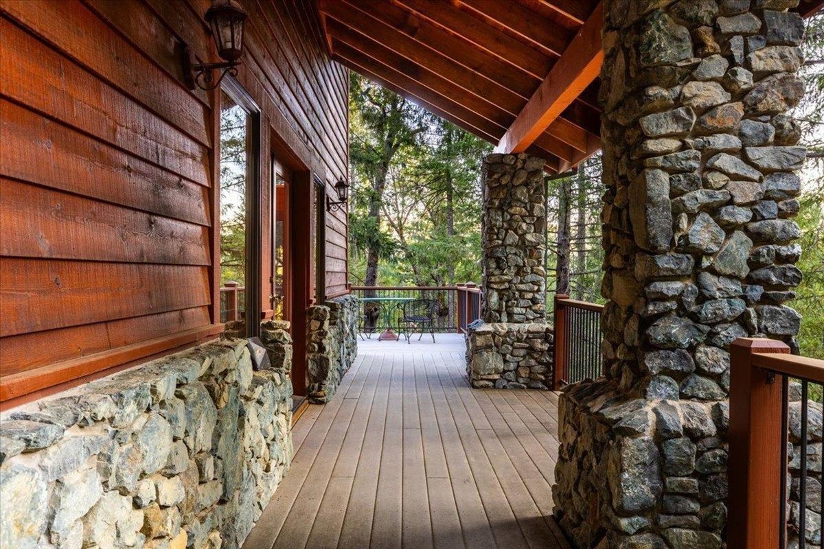 Covered wooden porch with stone columns along the side walkway.